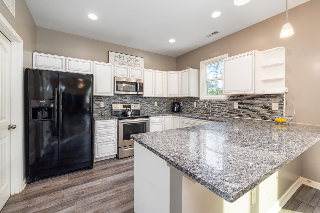 Elegant kitchen with sleek granite countertops and black appliances, perfect for modern living.